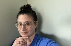 woman with brown hair in a bun wearing glasses