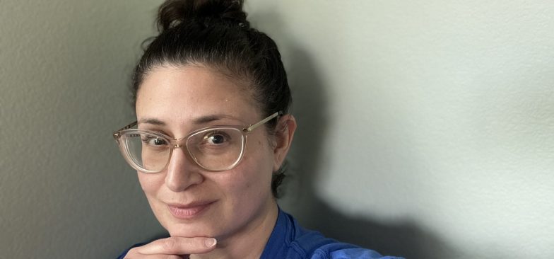 woman with brown hair in a bun wearing glasses